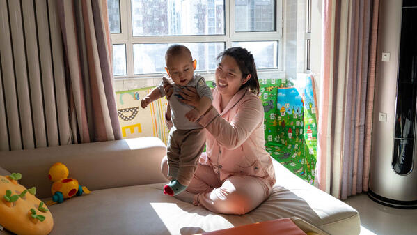 Su Yue and her son play in the living room of their house in Beijing, China 