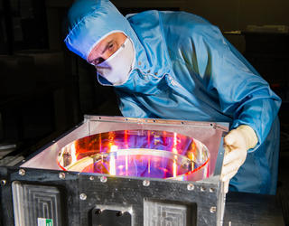 Engineer observing the reflective surface of a high precision mirror