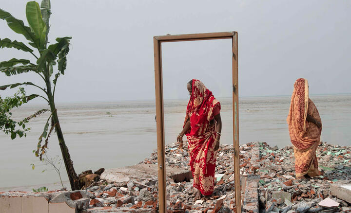 Two women stand on the remains of a house destroyed by erosion on the banks of the Padma River, Bangladesh.