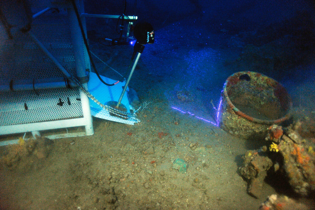 On the site of a shipwreck, a machine scans ancient pottery with a violet beam.