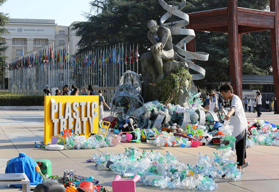 Benjamin Von Wong, right, a Canadian artist and activist, heaps piles of plastic waste onto a large sculpture that he designed. 