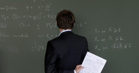 Man facing a blackboard full of equations.
