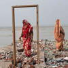 Two women stand on the remains of a house destroyed by erosion on the banks of the Padma River, Bangladesh.