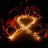 Members of a non government organisation make a red ribbon, the universal symbol of awareness and support for those living with HIV, with candles on the eve of World AIDS day in Ahmedabad, India, Tuesday, Nov. 30, 2021