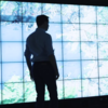 ©CNRS Images Man standing in front of wall of screens.
